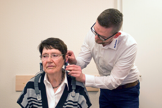 Ein Hörakustiker testet das Hörvermögen einer älteren Frau mit modernen Hörgeräten.